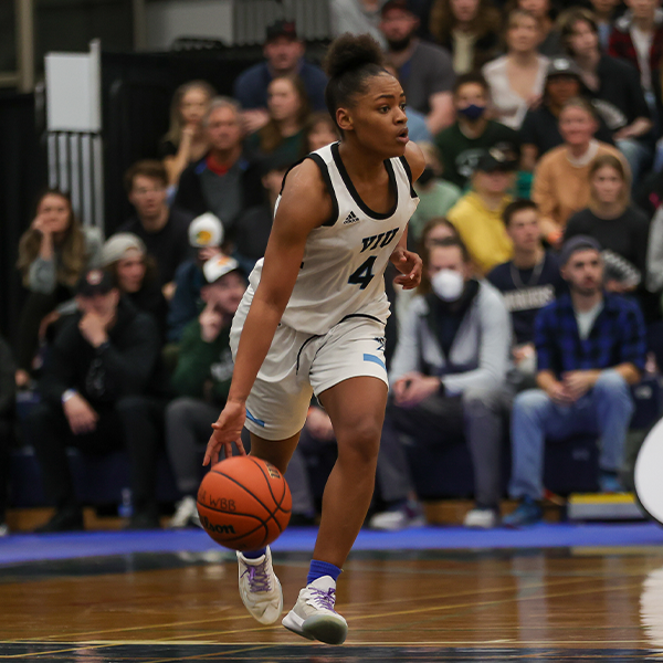 A female student-athlete dribbles a basketball