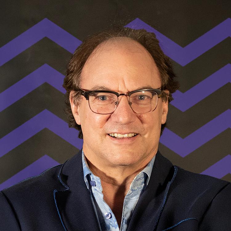Smiling man wearing glasses with a purple mountain pattern behind him