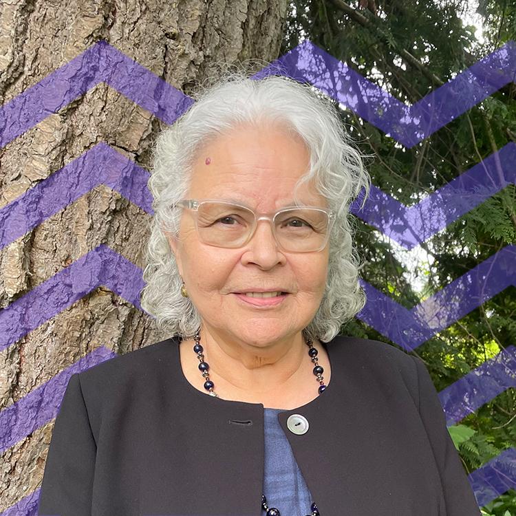 Woman with white hair and glasses standing by a tree with a purple mountain pattern behind her
