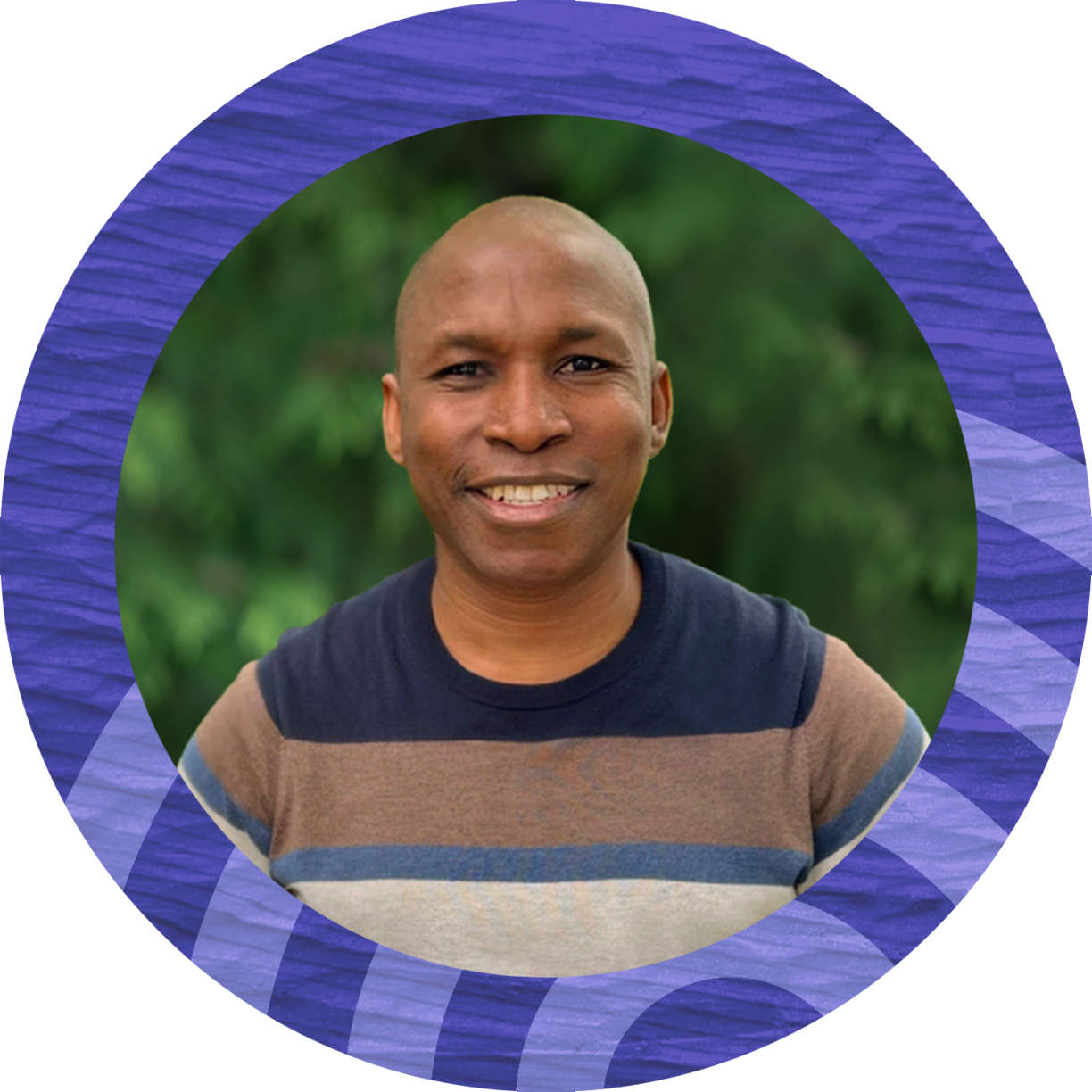 Smiling man wearing a multicolored sweater and standing in front of trees