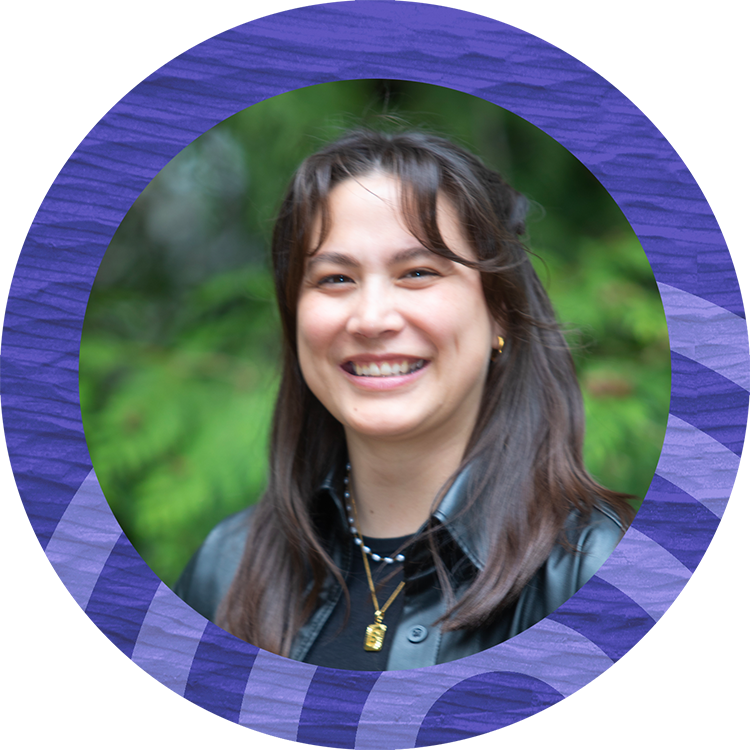 Smiling young woman with dark hair standing in front of trees