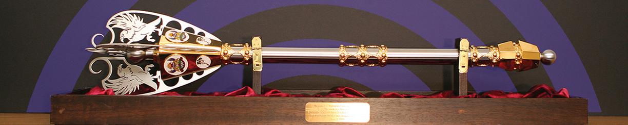 Gold-plated ceremonial mace mounted on a wooden stand