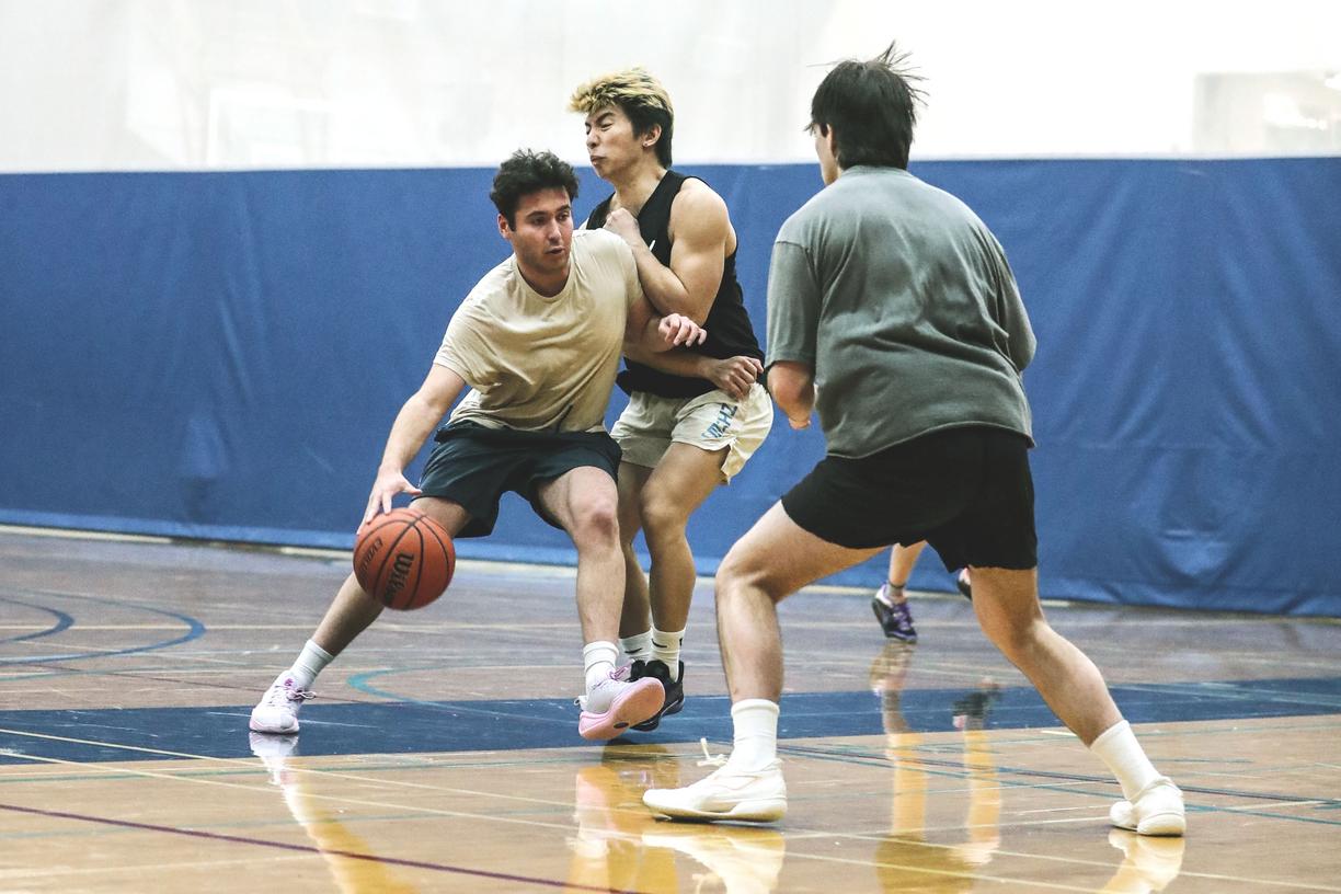 Three men compete on a basketball court