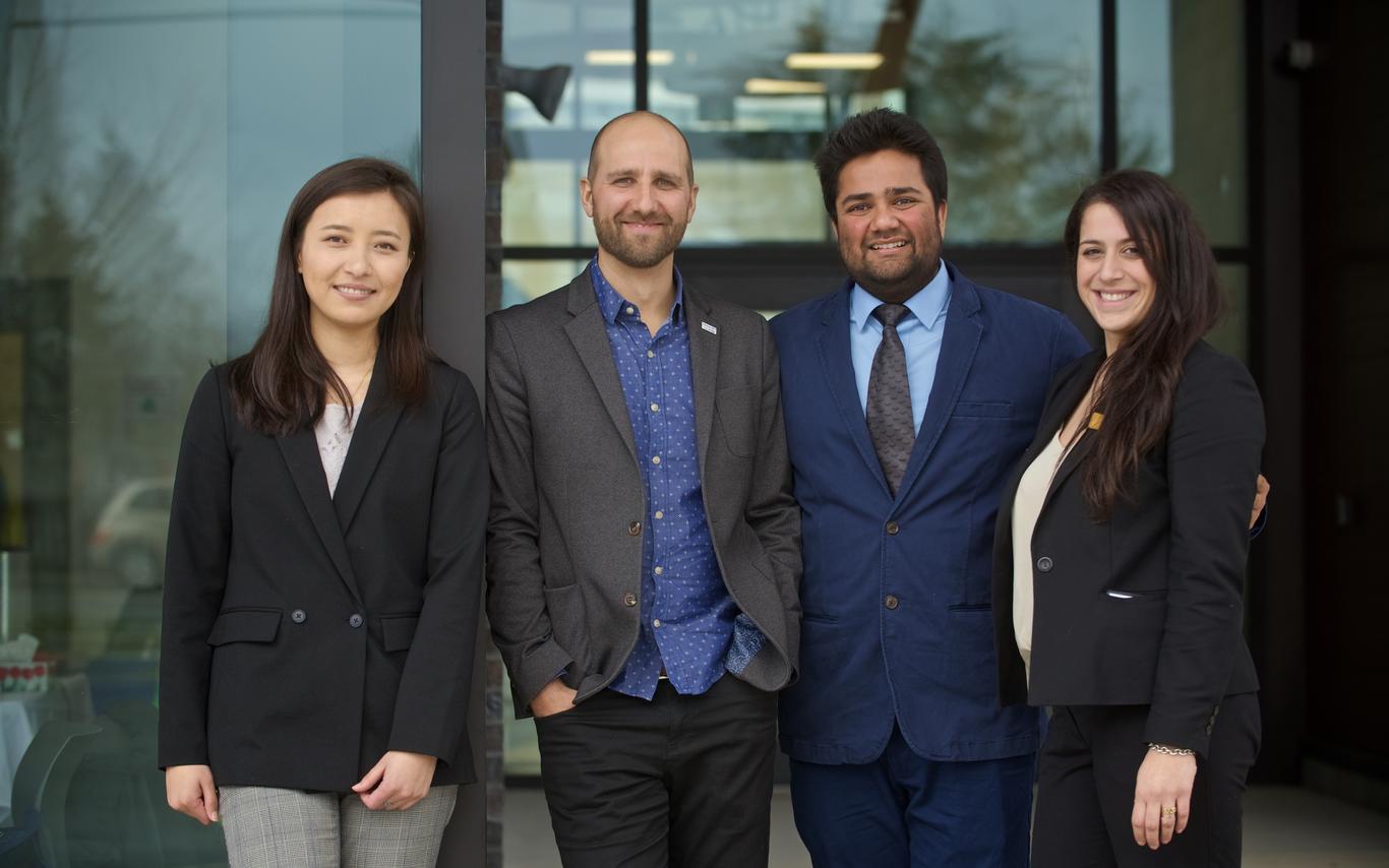 Four MBA students in business attire standing together for a photo