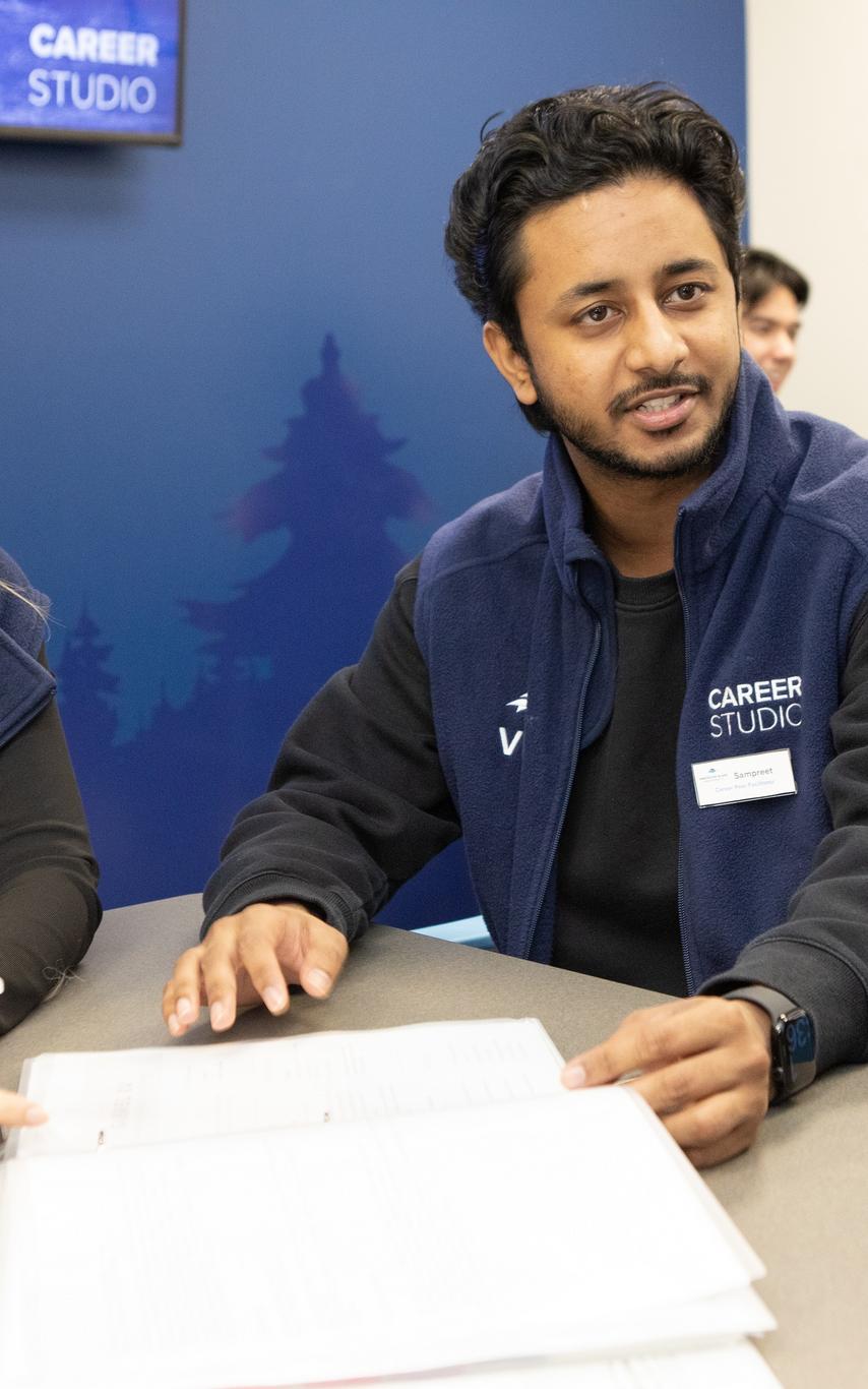 Female and male Career Studio team members talking to a student