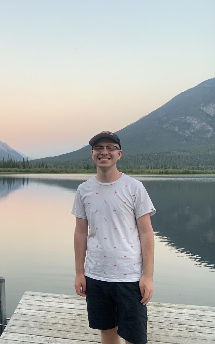 Owen Eshelby, Recreation and Tourism Student standing on a dock in front of a lake