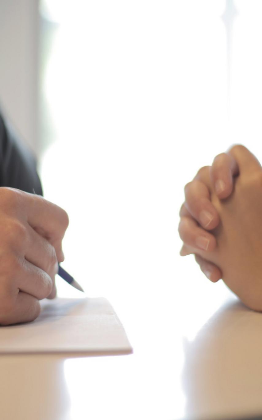 Hands of two people sitting at a table participating in an interview.